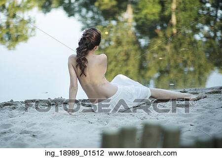 Stock Image - Pregnant wife lying on the white beach. Fotosearch