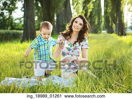 Stock Image - Pretty mother playing with her little son on the blanket. Fotosearch