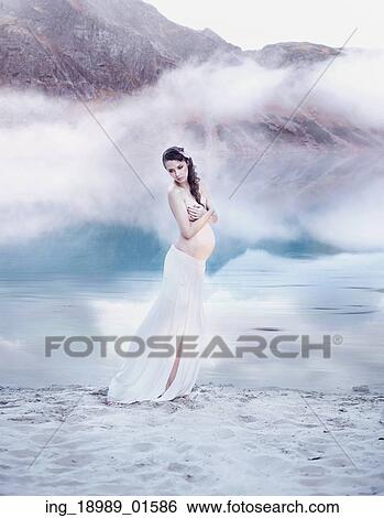 Stock Photograph - Pretty pregnant nymph on the white lake beach. Fotosearch