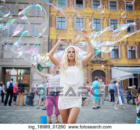 Stock Image - Pretty young blonde among lots of soap bubbles. Fotosearch