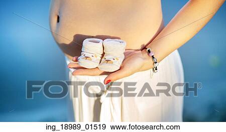 Prgenant woman holding cute, tiny baby shoes View Large Photo Image Stock Photo - Prgenant woman holding cute, tiny baby shoes. Fotosearch