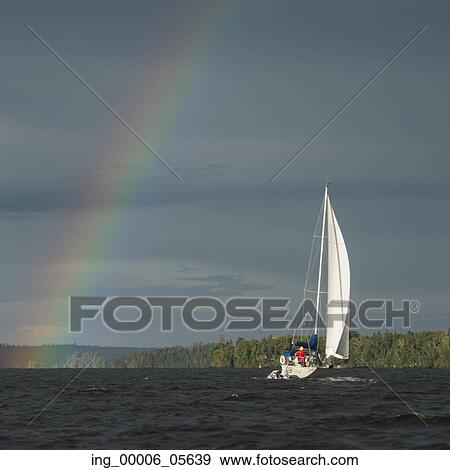 Stock Photo - Rainbow over a lake with a sailboat, Lake Of The Woods, Ontario, Canada. Fotosearch