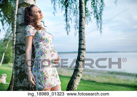 Realxed pregnant woman leaning against the tree View Large Photo Image Stock Image - Realxed pregnant woman leaning against the tree. Fotosearch