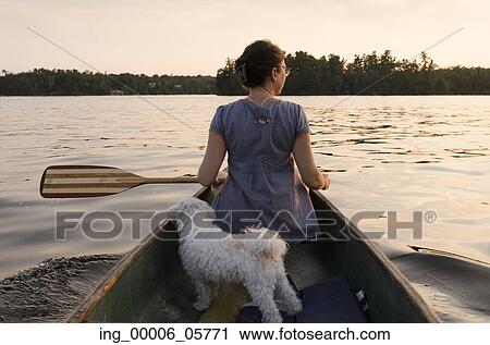 Stock Image - Rear view of a puppy with a woman in a canoe, Lake of the Woods, Ontario, Canada. Fotosearch