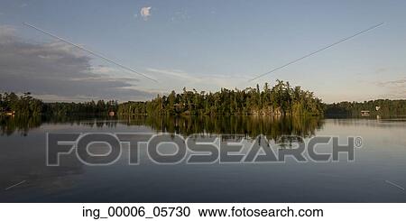 Stock Image - Reflection of trees on water, Lake Of The Woods, Ontario, Canada. Fotosearch