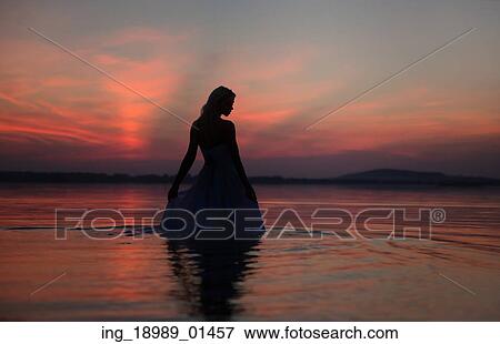 Stock Photo - Silhouette of the lady over the sunset background. Fotosearch