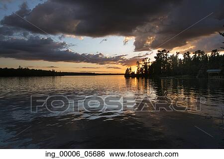 Silhouette of trees at lakeside during sunset, Lake Of The Woods, Ontario, Canada View Large Photo Image Stock Photograph - Silhouette of trees at lakeside during sunset, Lake Of The Woods, Ontario, Canada. Fotosearch