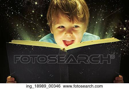 Stock Photograph - Small boy carrying an old magic book. Fotosearch