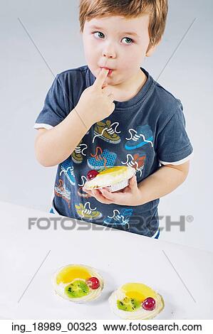 Stock Image - Small boy tasting the delicious fruit cake. Fotosearch