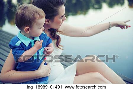 Stock Image - Smart mother indicating the pure lake . Fotosearch