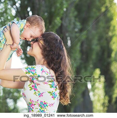 Stock Image - Tender mom tossing her baby child. Fotosearch