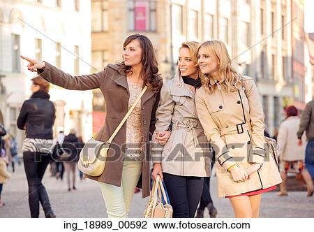 Stock Image - Three pretty women in the crowdy place. Fotosearch