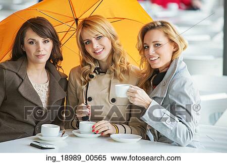 Stock Photography - Three pretty women, the coffee and the umbrella. Fotosearch