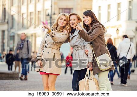 Stock Image - Three young girlfriends indicating something interesting. Fotosearch