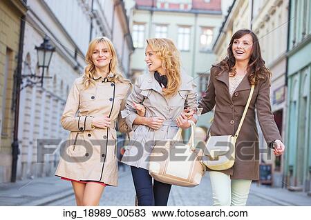 Stock Image - Two blonde and one brunette woman walking. Fotosearch