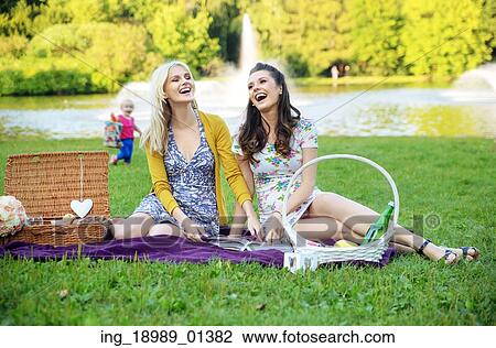 Stock Image - Two girlfriends laughing during summer picnic. Fotosearch