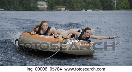 Two girls lying on an inflatable raft floating in a lake, Lake Of The Woods, Ontario, Canada View Large Photo Image Picture - Two girls lying on an inflatable raft floating in a lake, Lake Of The Woods, Ontario, Canada. Fotosearch