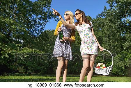 Stock Photo - Two joyful girls wearing trendy wooden sunglasses. Fotosearch