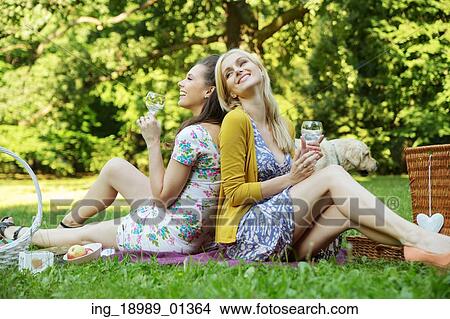 Two joyful ladies sitting on the blanket View Large Photo Image Picture - Two joyful ladies sitting on the blanket. Fotosearch
