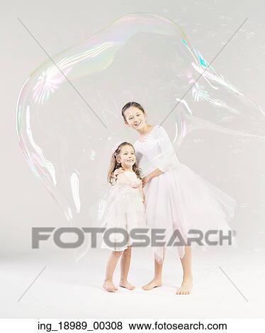 Stock Photo - Two sisters with the large soap bubble. Fotosearch