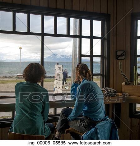 Two women sitting on chairs looking at a view, Puerto Natales, Patagonia, Chile View Large Photo Image Stock Photography - Two women sitting on chairs looking at a view, Puerto Natales, Patagonia, Chile. Fotosearch