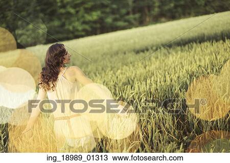Stock Image - Vacation picture of the young woman among the corn crop. Fotosearch