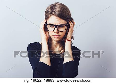 Stock Image - Woman in glasses, adjusts his glasses or hair on a grey background. Fotosearch