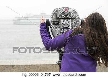 Stock Photo - Woman using binoculars at Upper New York Bay, Ellis Island, Jersey City, New York State, USA. Fotosearch