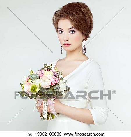 Stock Image - Woman with bouquet of flowers in her hands. Flowers. Spring. Bride. March 8. Fashion photo. Fotosearch