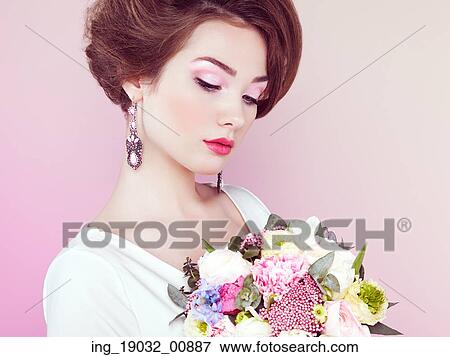 Stock Photo - Woman with bouquet of flowers in her hands. Flowers. Spring. Bride. March 8. Fashion photo. Fotosearch