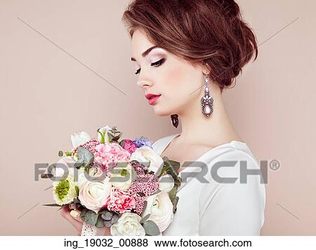 Stock Photo - Woman with bouquet of flowers in her hands. Flowers. Spring. Bride. March 8. Fashion photo. Fotosearch