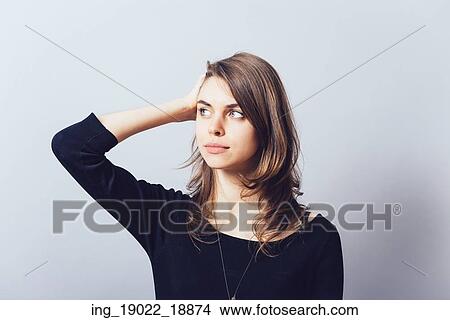 Picture - Woman with hand on head, straightens the hair. Fotosearch