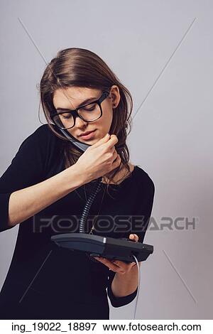Stock Photo - Woman with office or home phone. On a gray background.. Fotosearch