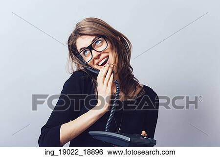 Stock Photograph - Woman with office or home phone. On a gray background.. Fotosearch