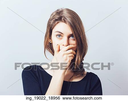 young adult woman holding hand over her mouth over grey background View Large Photo Image Stock Photograph - young adult woman holding hand over her mouth over grey background. Fotosearch