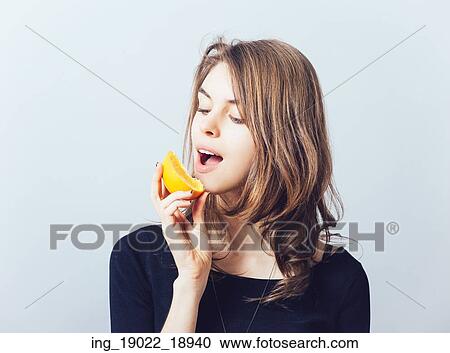 Stock Image - young beautiful woman with citrus orange fruit having fun. . Fotosearch