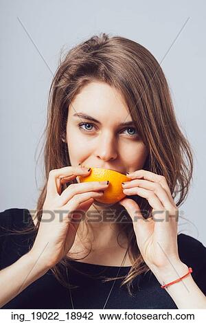Stock Image - young beautiful woman with citrus orange fruit having fun. . Fotosearch