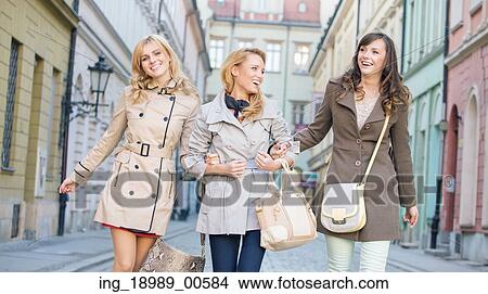 Picture - Young female friends walking and laughing. Fotosearch