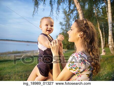 Young mom making her baby laughing View Large Photo Image Stock Photo - Young mom making her baby laughing. Fotosearch