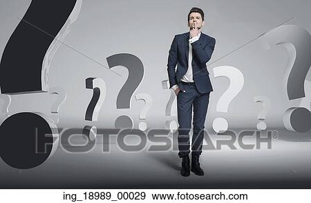 Stock Photo - Young smart businessman among question marks. Fotosearch