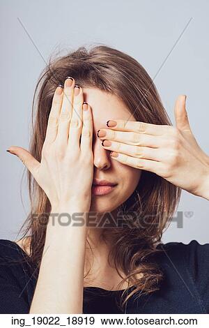 Stock Photo - Young teen woman covering her eyes isolated on a gray background. Fotosearch