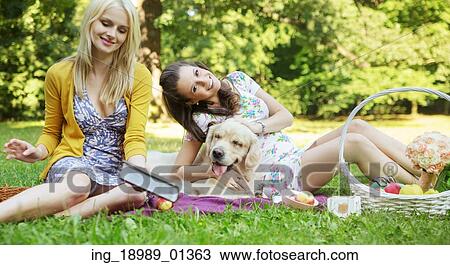 Stock Image - Young women playing with friendly dog. Fotosearch