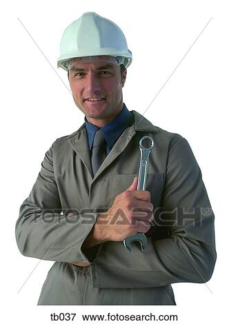 Photograph of a non-specific tradesman wearing overalls, a hard hat and holding a ring spanner View Large Photo Image Stock Photo - Photograph of a non-specific tradesman wearing overalls, a hard hat and holding a ring spanner. Fotosearch