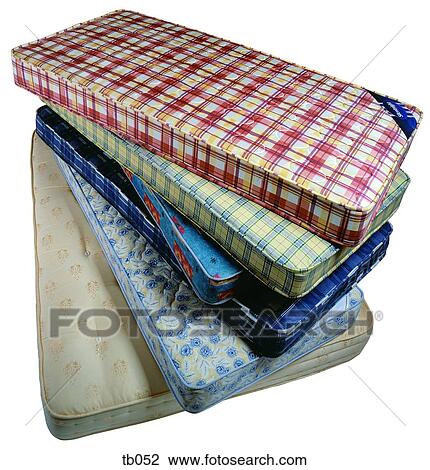 Stock Image - Photograph of a stack of various coloured single bed mattresses. Fotosearch