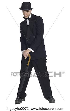 Stock Image - Man in tuxedo and black bowler leaning on umbrella . Fotosearch