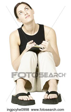 Stock Photo - Smiling young woman thinking and writing in book. Fotosearch