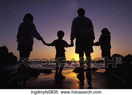 Stock Photography - Family Standing on the Beach at Sunset. Fotosearch