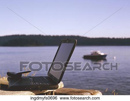Stock Photograph - Laptop and Cell Phone by the Lake. Fotosearch