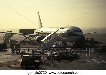Stock Image - Service Vehicles Surrounding an Airplane. Fotosearch