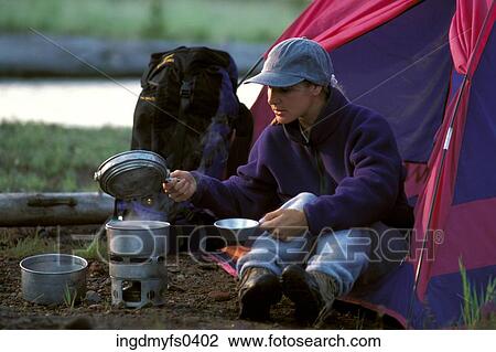 Stock Image - Woman Cooking Over Campfire. Fotosearch